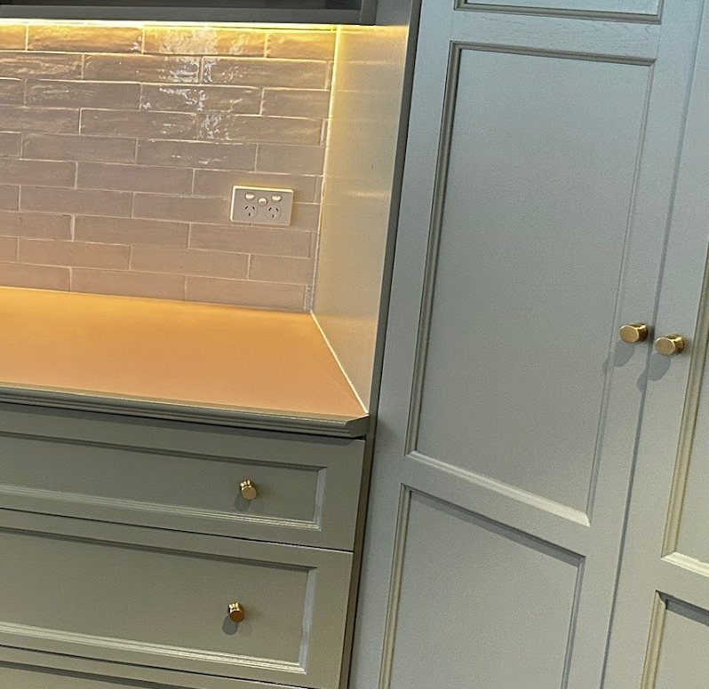Kitchen drawers and pantry doors freshly painted in sage green with brass knobs