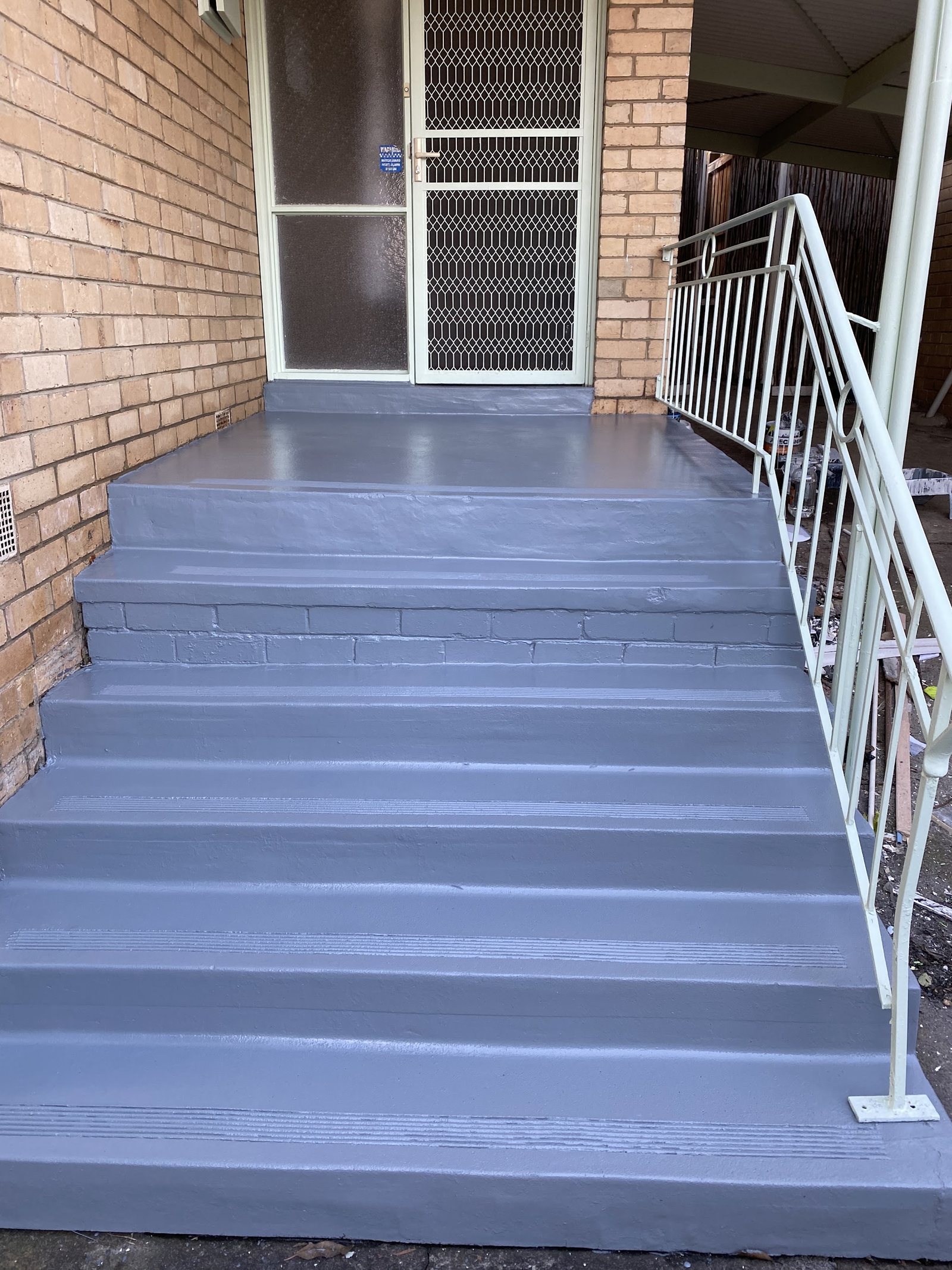 Brick unit entrance with the concrete steps freshly painted in grey non-slip finish