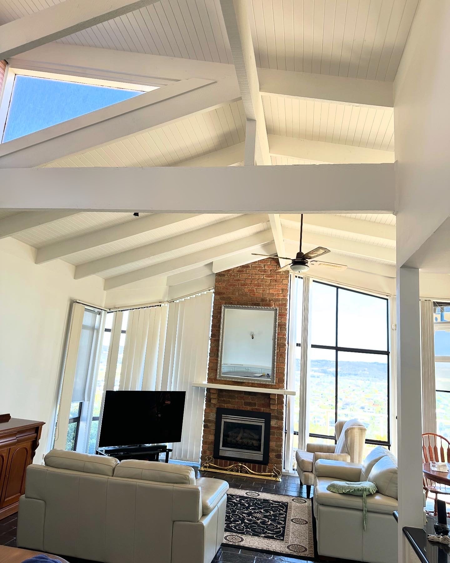 Vaulted living room with a freshly painted white lining-board ceiling and exposed beams